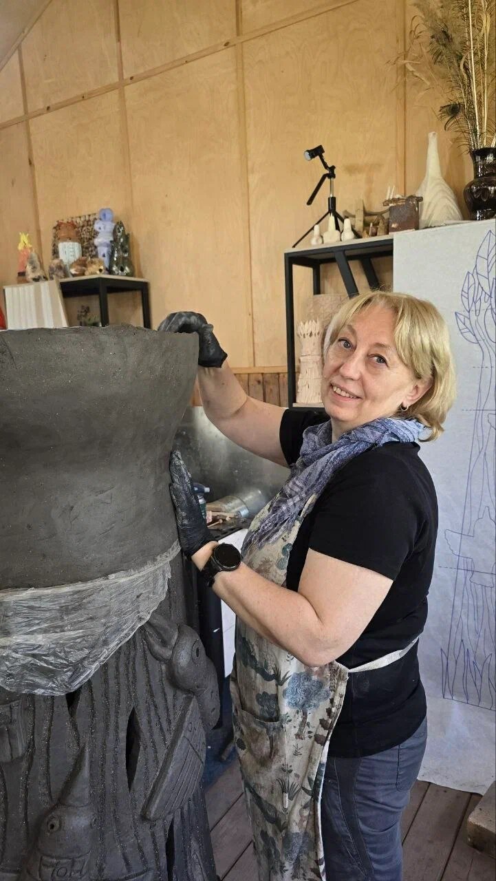 Мастер вручную выравнивает поверхность крупной керамической формы